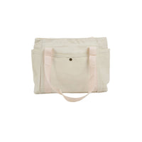 Light canvas tote bag with wide front pocket, long handles, and snap button closure.