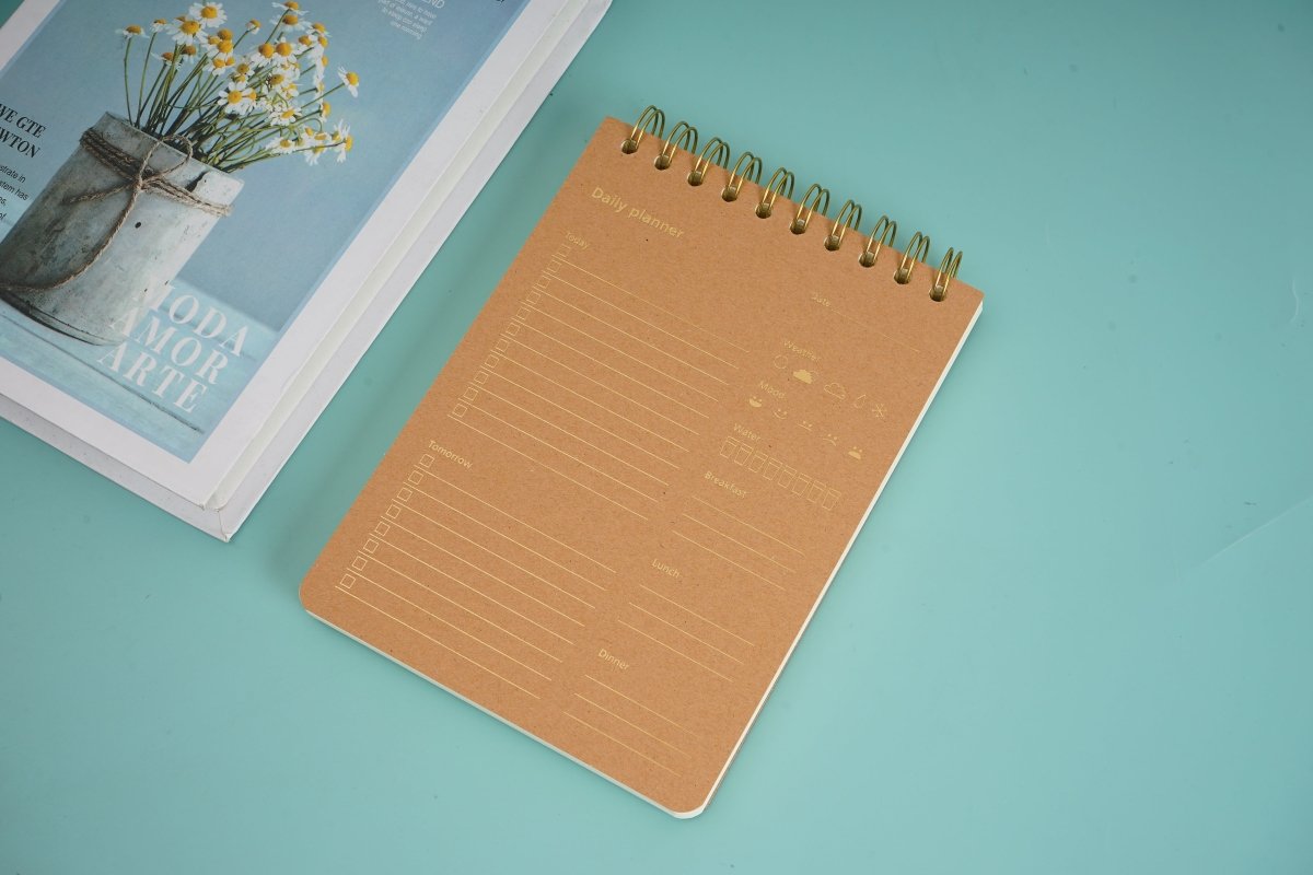 Wood-grain coil notebook with tan cover and gold spiral rings, top view