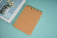 Wood-grain coil notebook with tan cover and gold spiral rings, top view