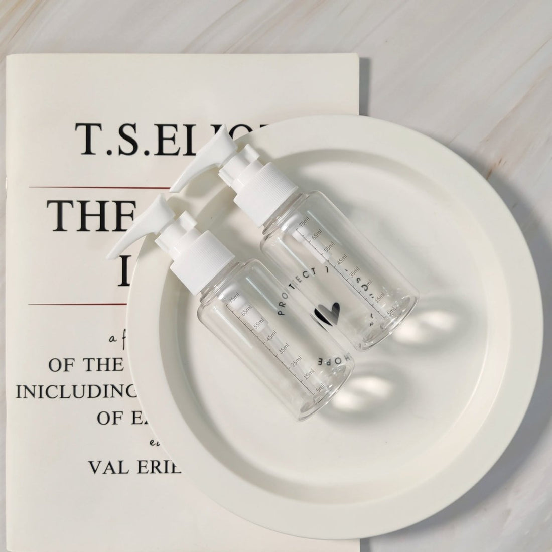 Two small plastic pump bottles with white nozzles on a round tray