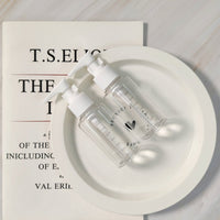 Two small plastic pump bottles with white nozzles on a round tray