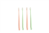 Four soft bristle toothbrushes with peach, green, and pink handles