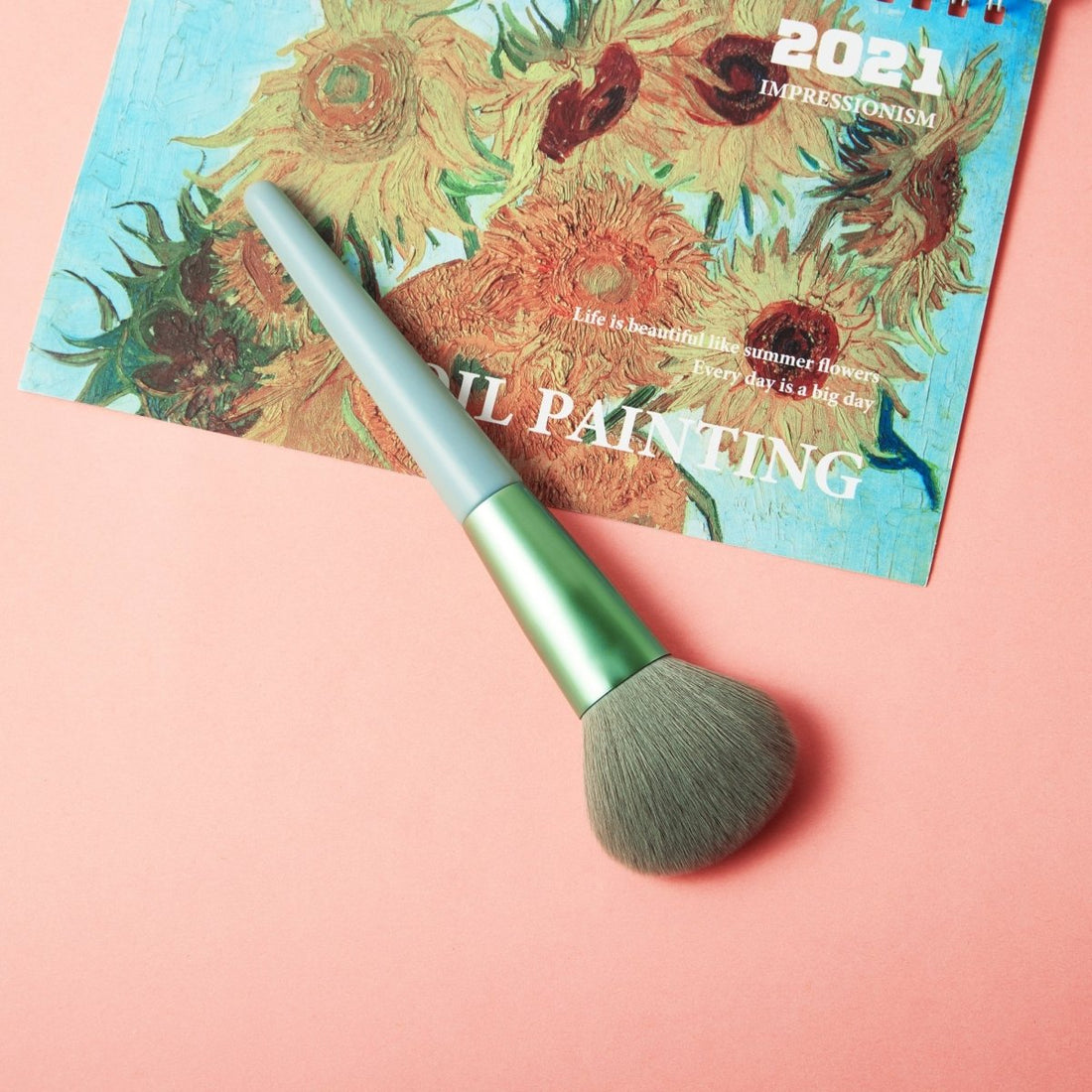 Soft powder brush at an angle, green ferrule and gray tapered bristles