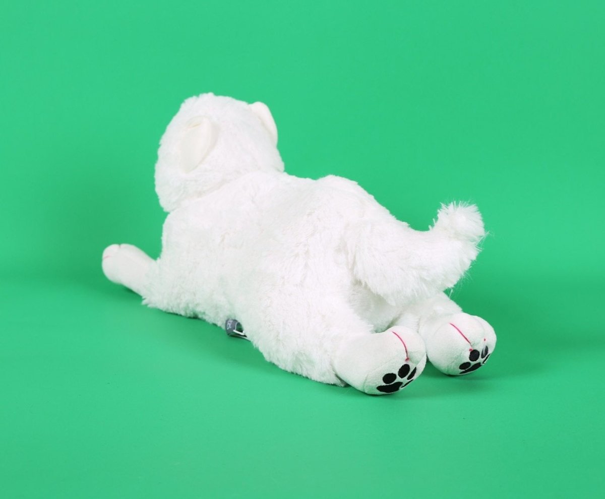 White plush puppy toy lying on its side, paws tucked forward, paw pads visible