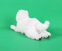 White plush puppy toy lying on its side, paws tucked forward, paw pads visible