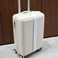 Star print luggage strap attached to a white rolling suitcase with black hardware