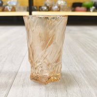 Clear amber glass tumbler with faceted texture, thick bottom.