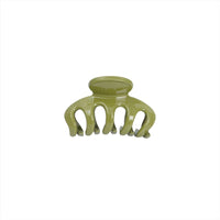 Green plastic hair clip with curved design and multiple teeth