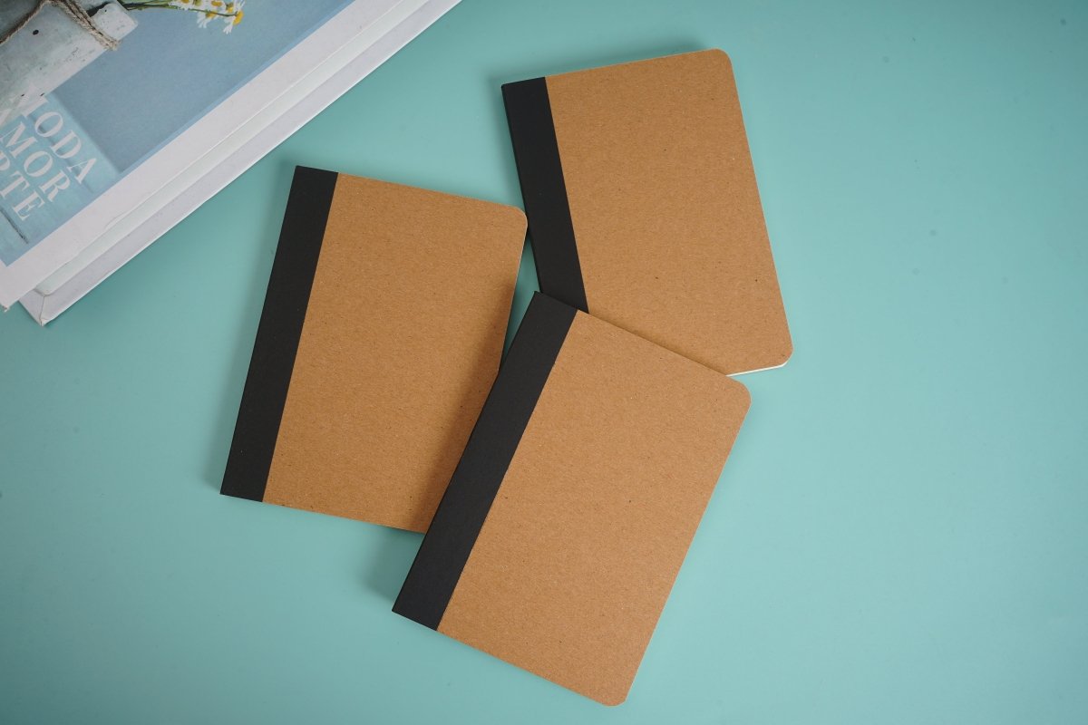 Kraft paper notebook with brown covers and black elastic strap, angled view.