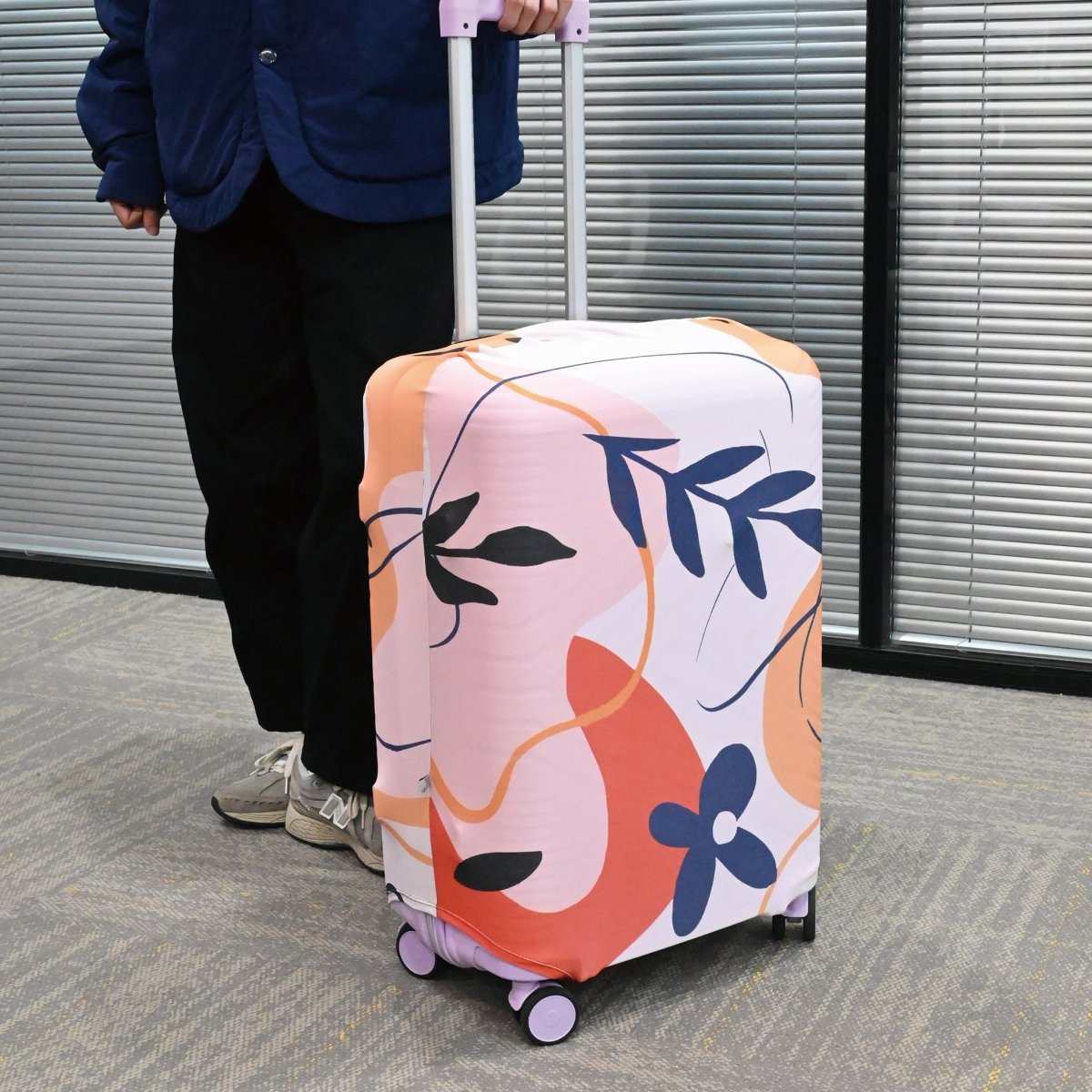 Floral luggage cover on upright suitcase, pink and navy abstract floral pattern