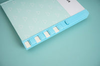 Blue notebook spine edge with page tabs and hardback cover detail