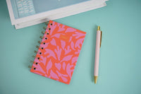 Pink notebook with purple coil and matching pen, coral patterned cover