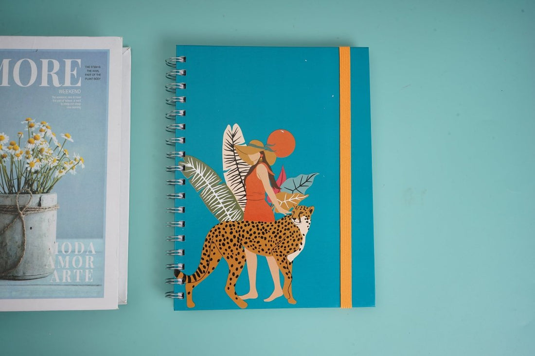 Teal coil notebook with illustrated leopard figure and orange vertical stripe on cover