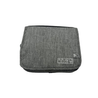 Grey travel bag with foldover flap and small front patch with icons