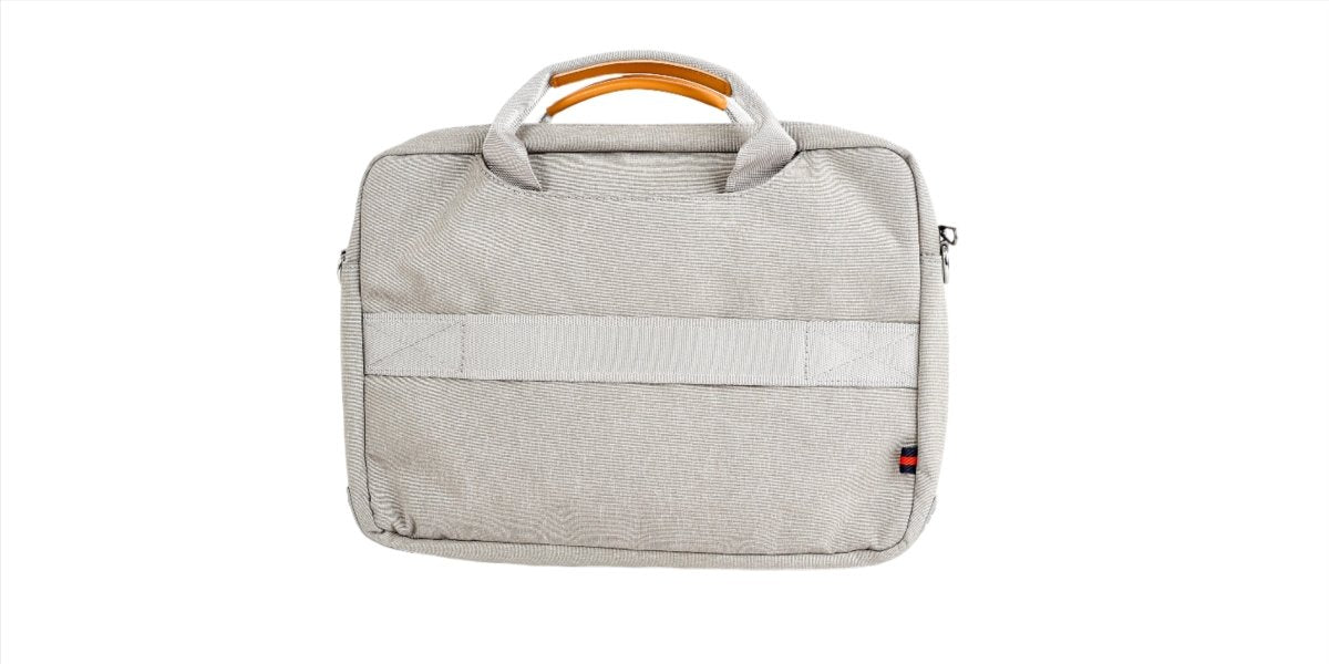 Light gray laptop bag front view with top handle, front panel seam, and small red tag