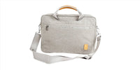 Light gray laptop bag 3/4 view with shoulder strap, side zip details, and orange handle