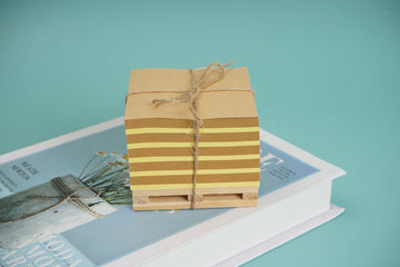 Wooden memo pad with stacked note sheets tied in twine on a wooden base