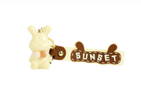 Rabbit keychain with 'SUNSET' charm on brown strap and small key ring