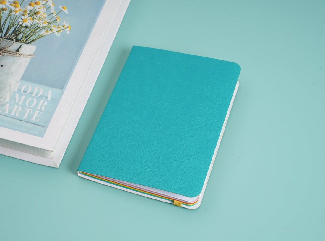 Teal notebook with colorful page edges and white pages visible