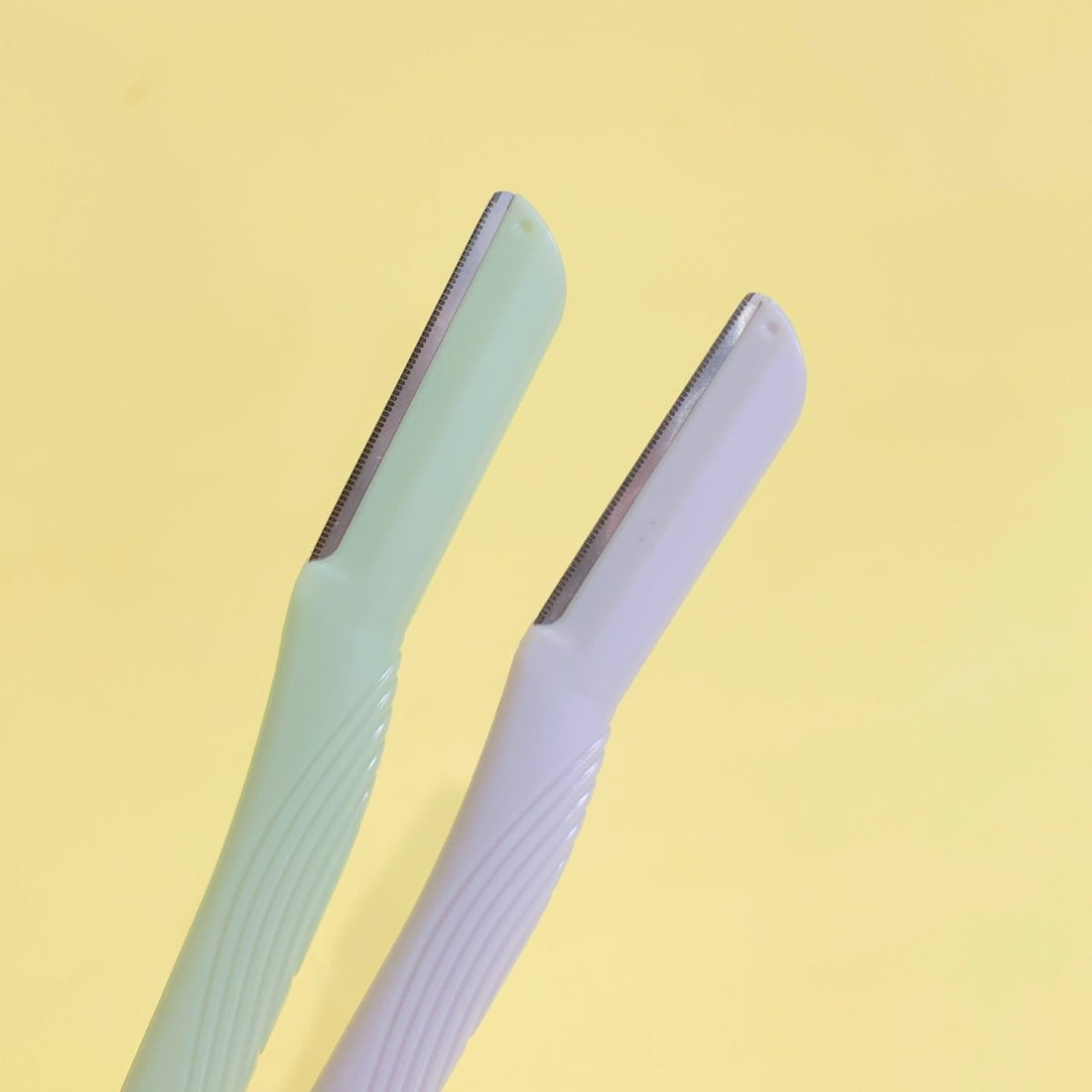Precision facial razors with protective caps, light blue and lavender, close-up handles