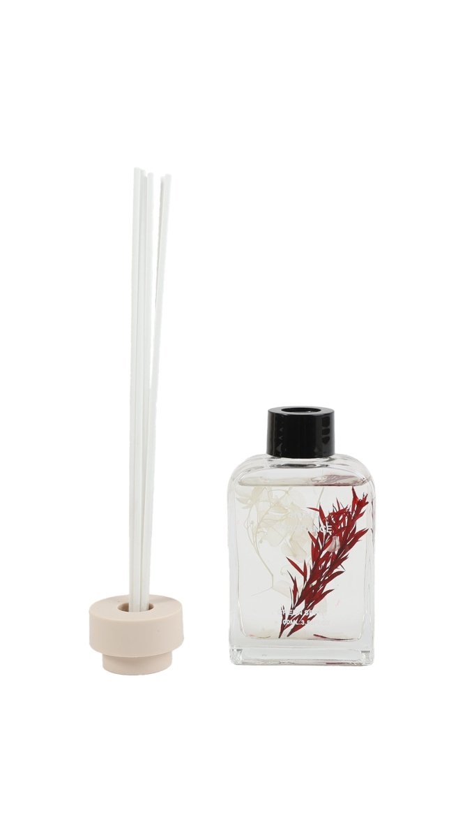Reed diffuser bottle with white reeds, black cap, clear glass and red botanical print