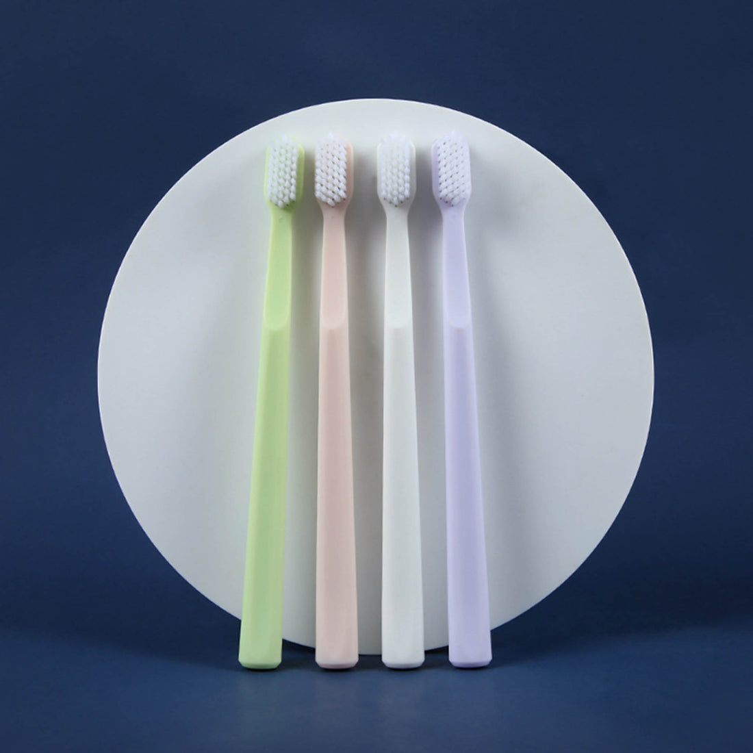 4-pack toothbrushes with white bristles on green, pink, white, and purple handles