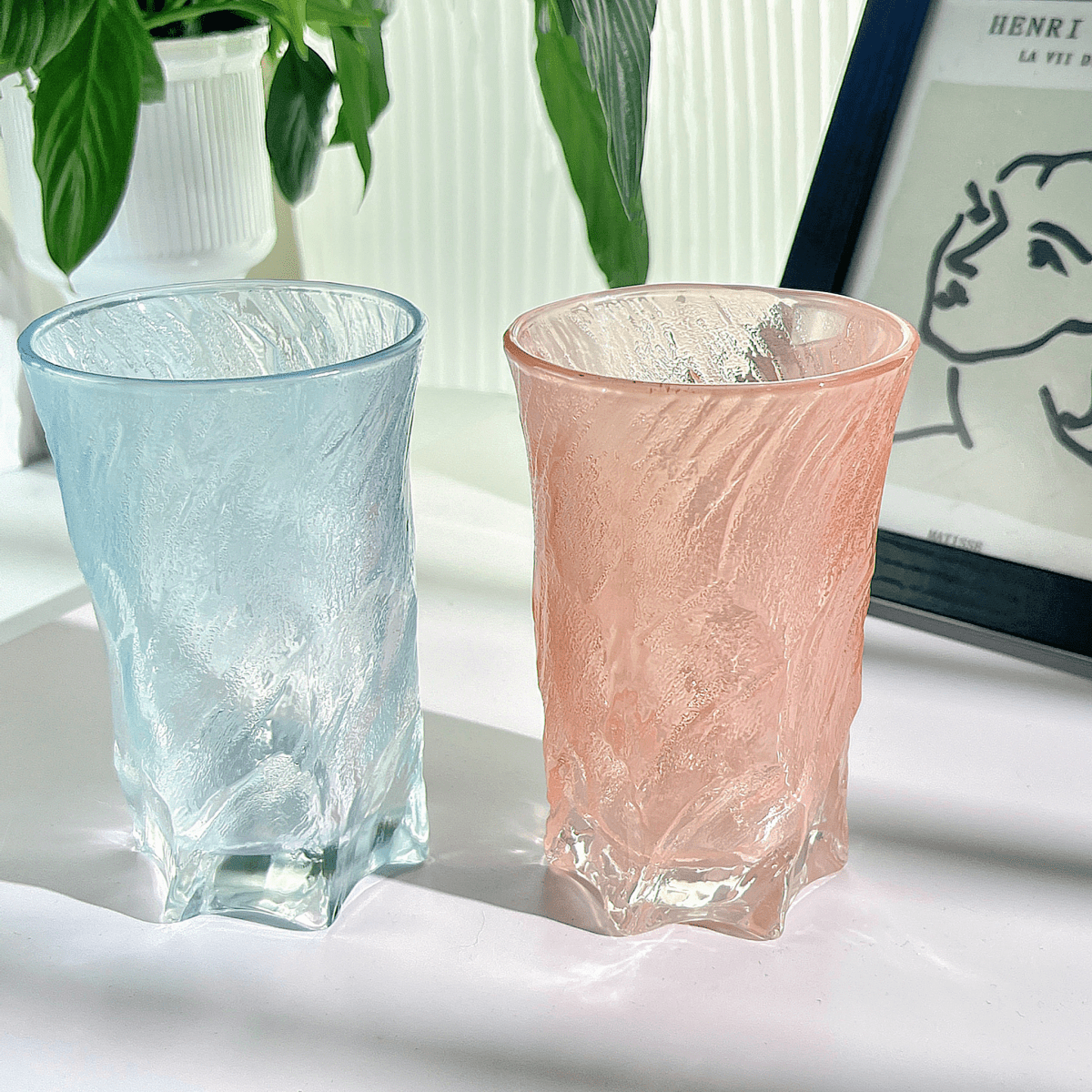 Two 300ml glass cups—blue and pink—with textured clear finish, cylindrical