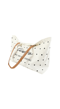 White tote bag with black polka dots, brown handles, angled view with center print