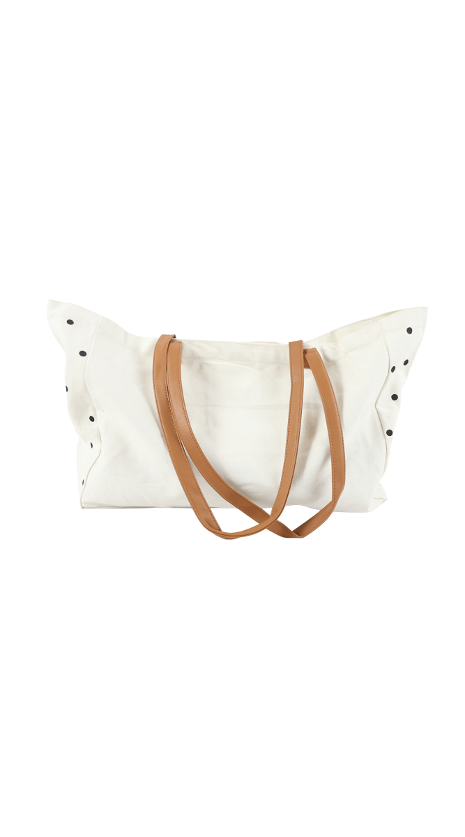 White tote bag with black polka dots and brown handles, open top view