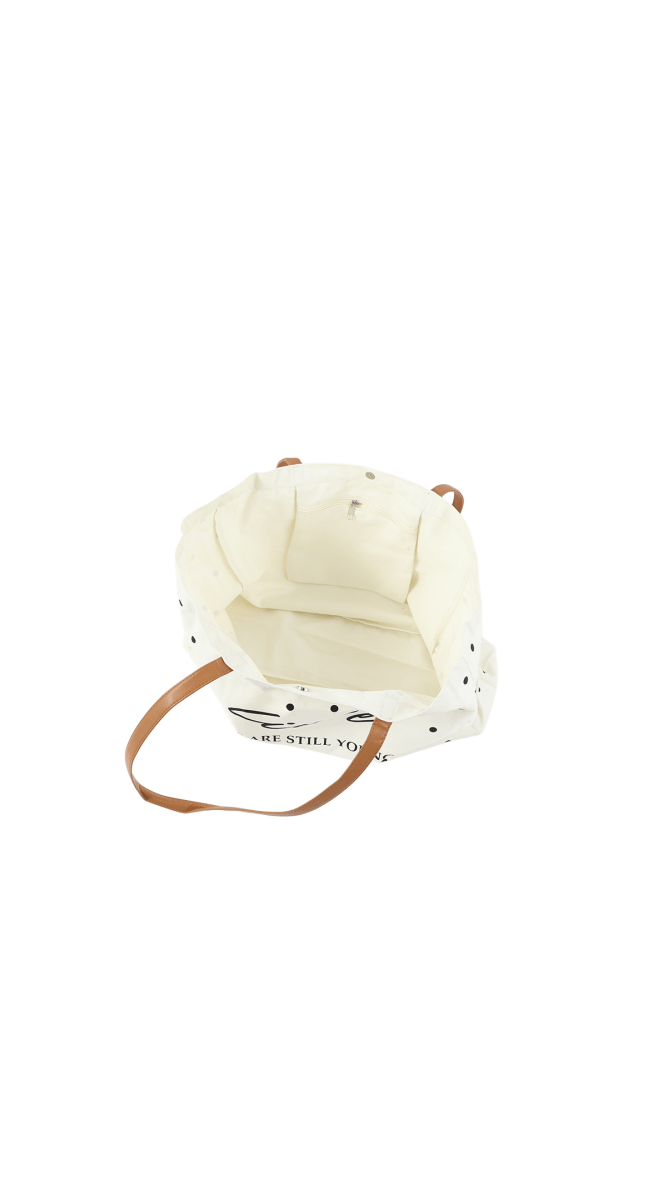 White tote bag with black polka dots and brown handles, folded compact view