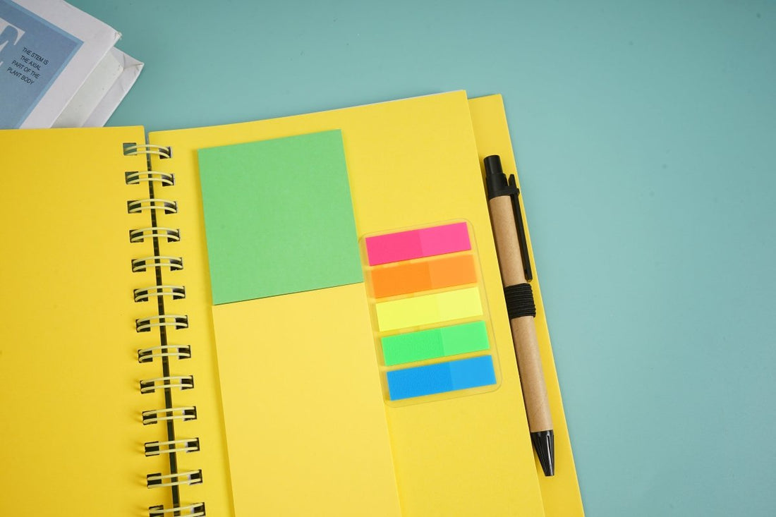 Large yellow coil notebook with pen, green and multicolor sticky notes inside