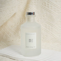 Reed diffuser bottle with Peach Oolong Tea label and silver cap