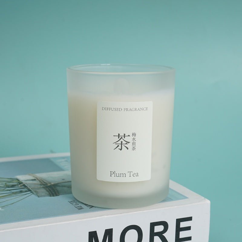 Plum tea scented candle in frosted glass jar on a surface